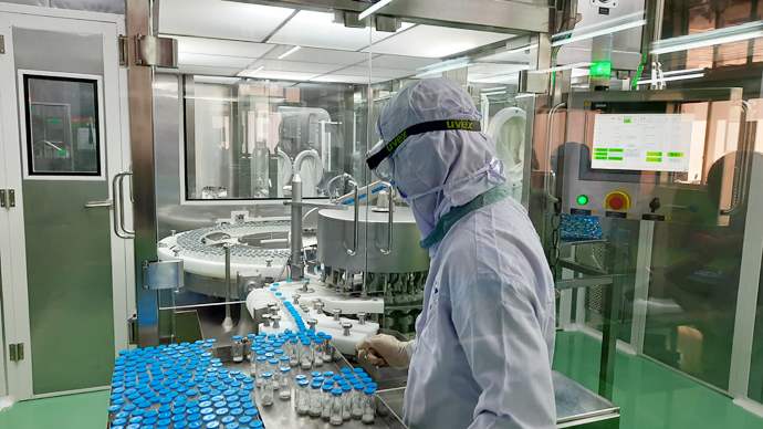 Công nhân đang giám sát sản xuất dược phẩm trên dây chuyền tự động, khép kín